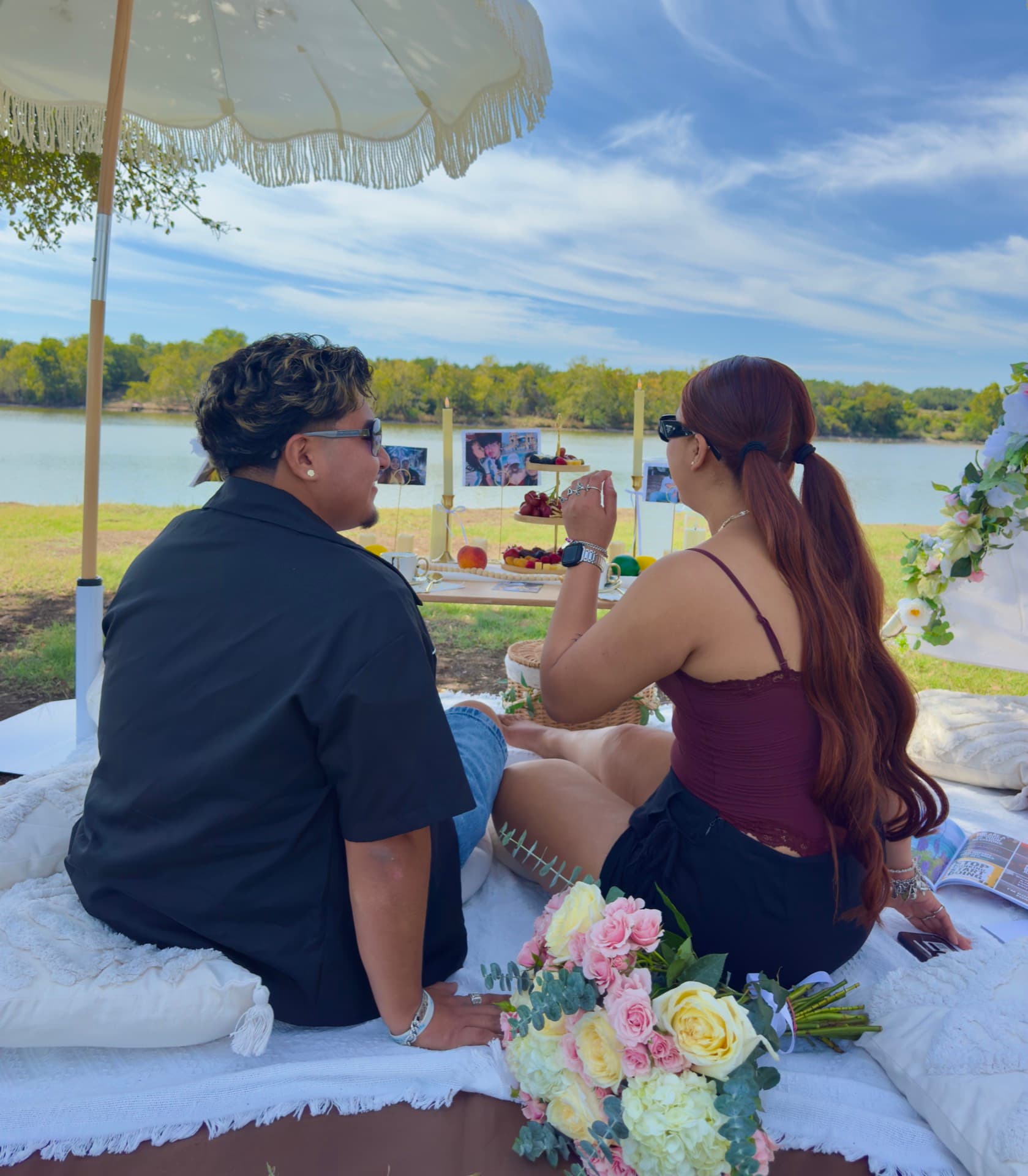 Pareja disfrutando de un pícnic junto al lago con un ramo de rosas en Austin