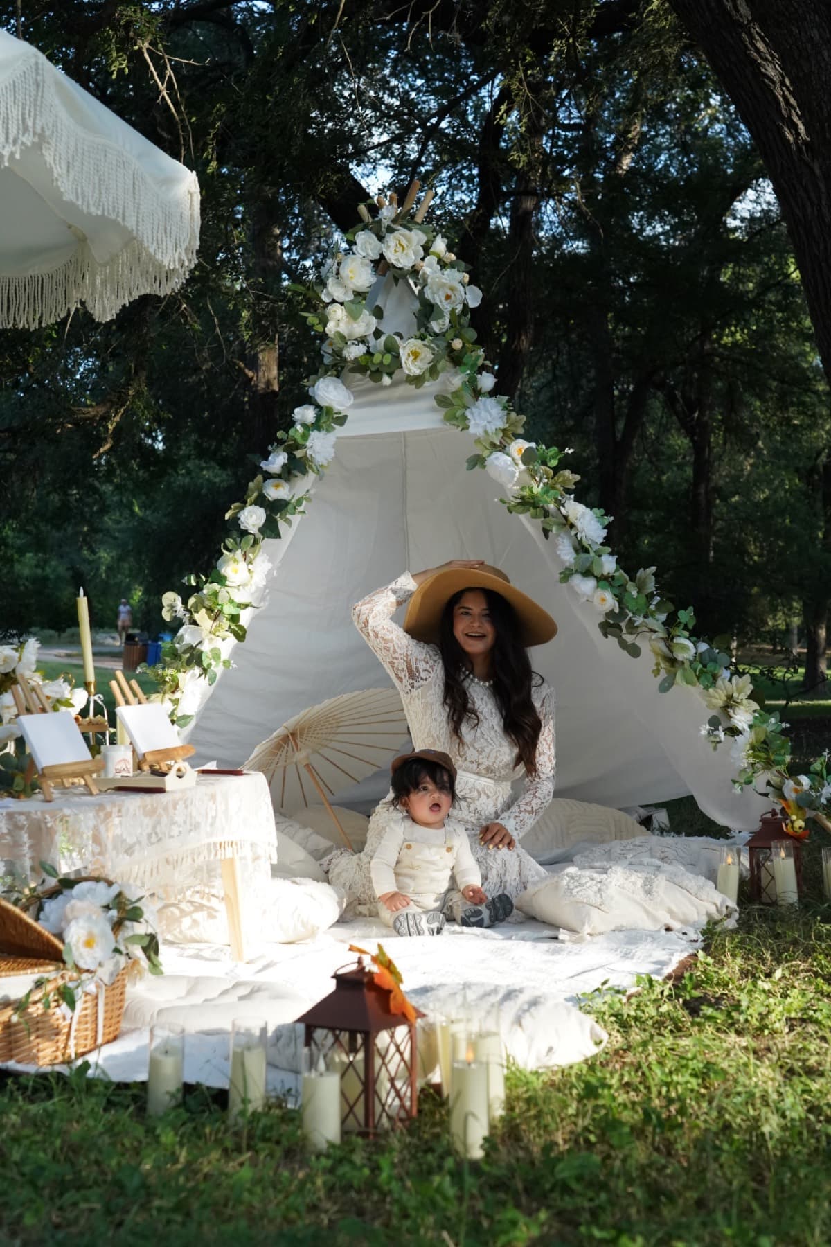 Madre y bebé en una carpa boho blanca cubierta de flores en Austin